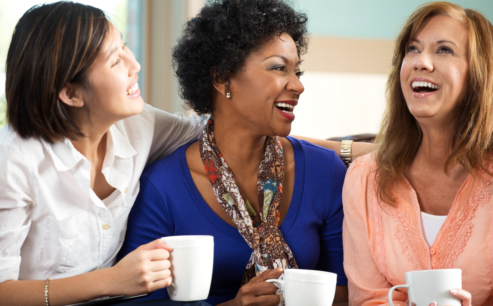 photo of three woman drinking coffee and laughing