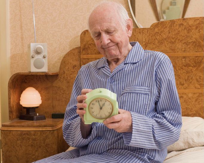 photo of older gentleman in pajamas holding a clock