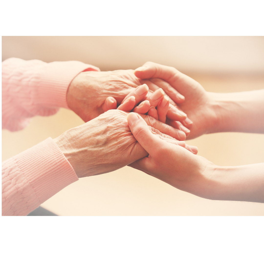 photo of younger person's  hands holding to older persons hands wearing an pink sweater