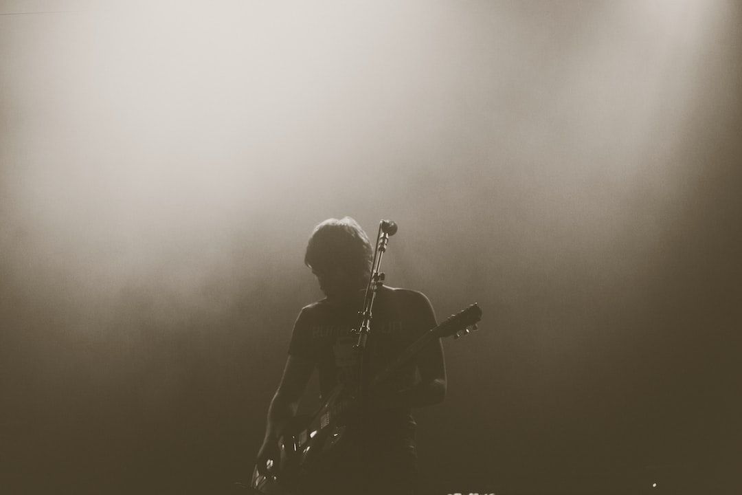 photo of a silhouette playing guitar and you can see a microphone in front of them