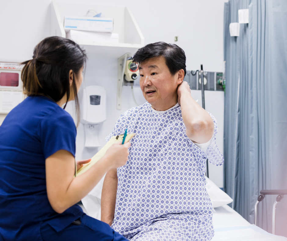 photo of man in hospital gown sitting on hospital bed holding his neck