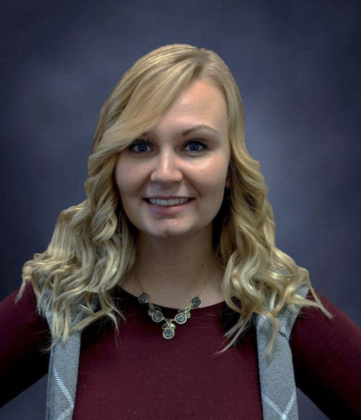 Image of a smiling, blonde woman with a formal portrait background