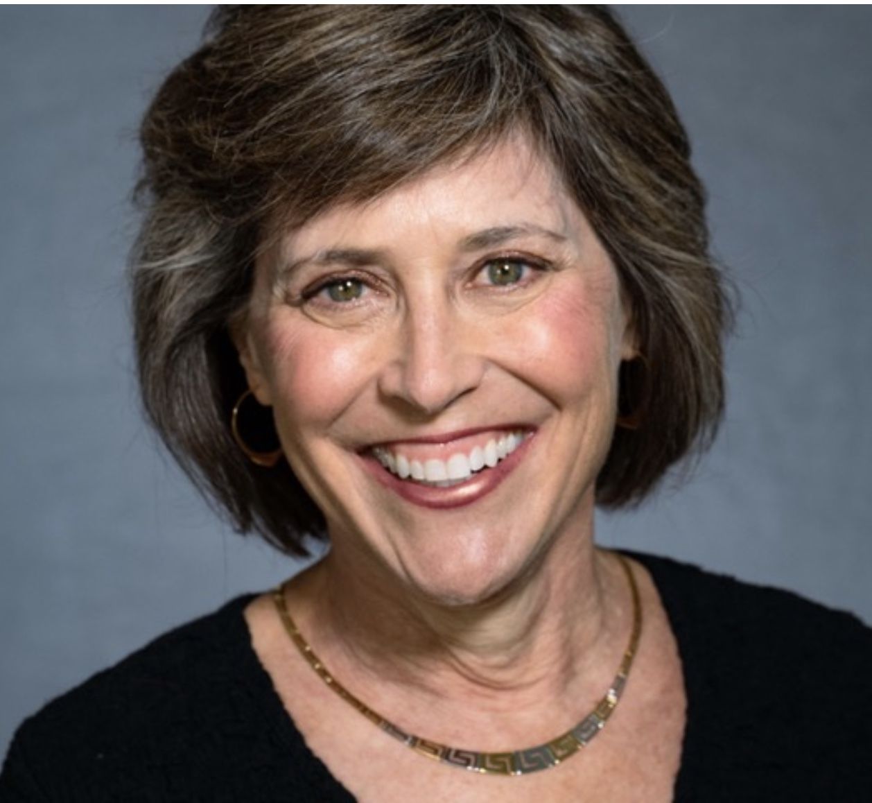 A smiling white woman in a black shirt on a professional background