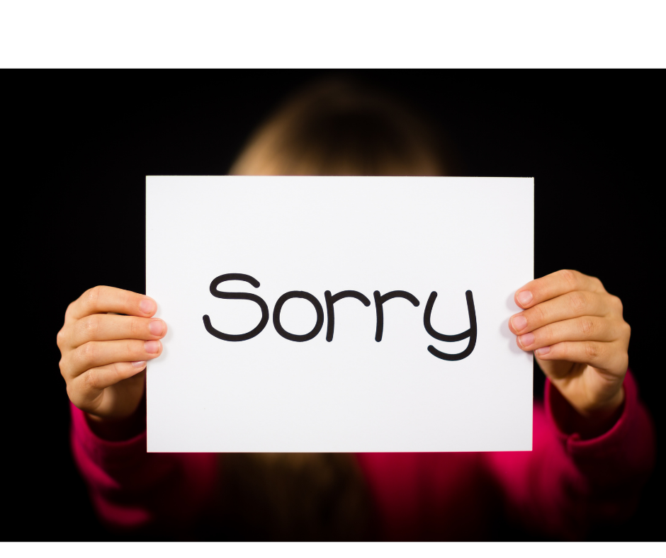 photo of hands holding white paper with black letters "SORRY"