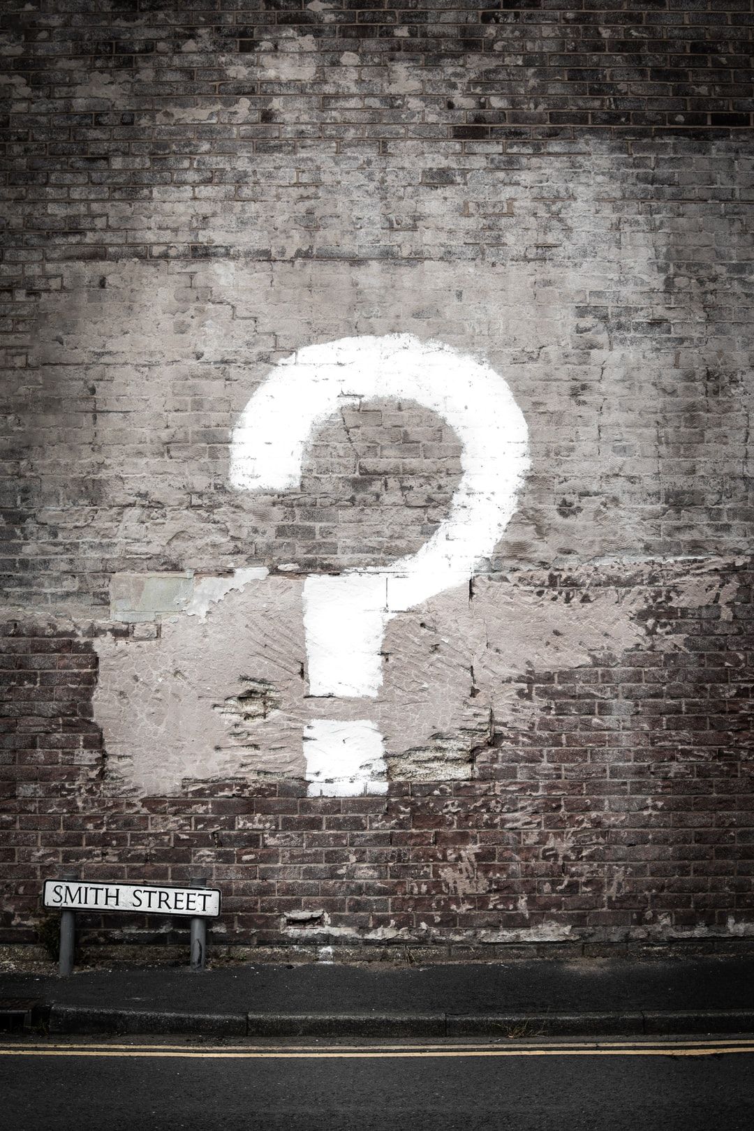 photo of brick wall with question mark painted in white