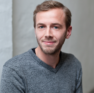 Nils Jacob-Wach von betterplace.org, junger Mann lächelnd vor grauem Hintergrund