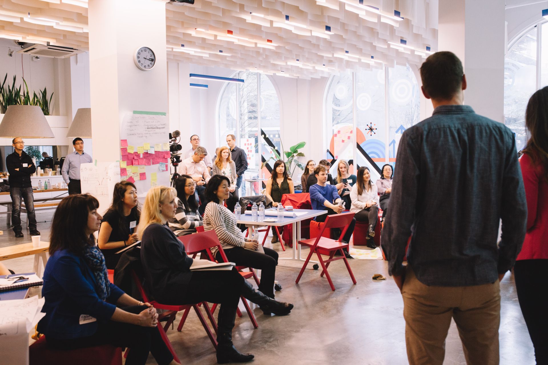 An audience listening to a group presenting work at a design thinking workshop