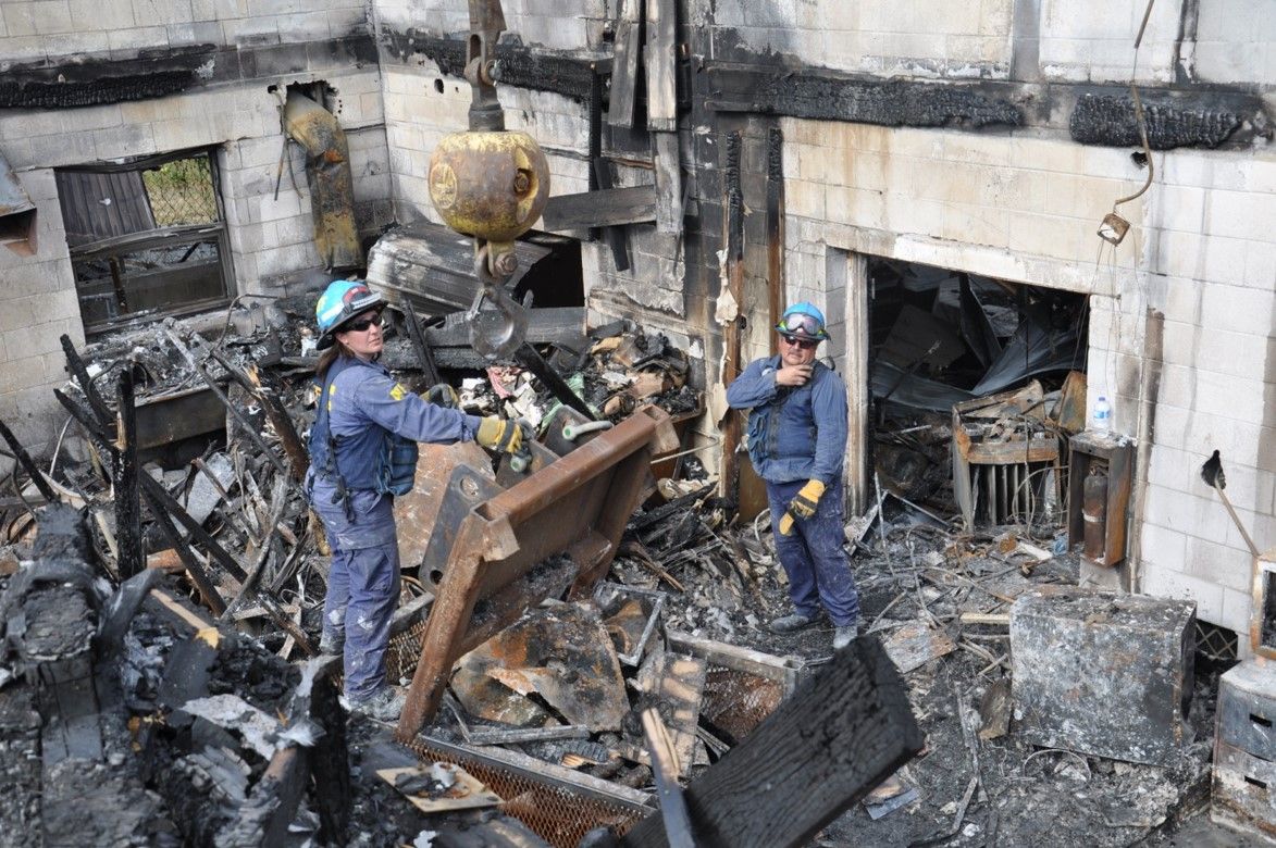Two fire investigators digging out a fire scene.