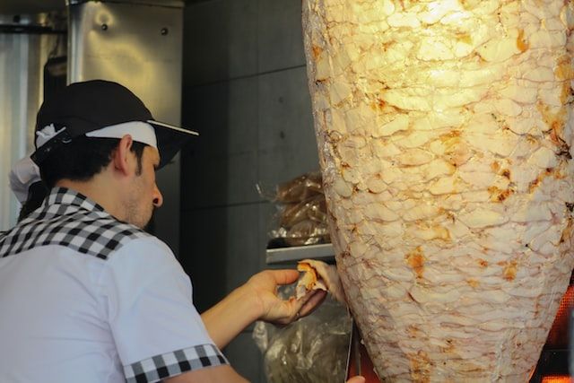 Safe Food preparing in Kebab shop - a chef is cutting cooked meat Controling Salmonella in food service restaurant