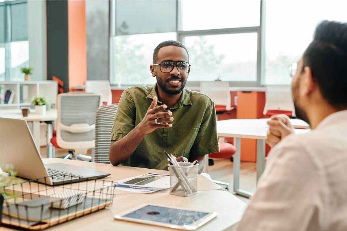 Dairy industry RMP Verifier/FSSC Auditor asking questions while interviewing the quality manager. The two gentlemen seated around a table discussing FSSC additional requirements.