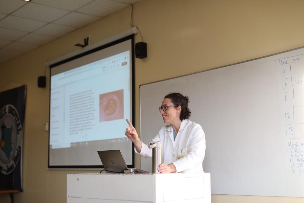 Dr. Andrea Parker teaching at a lectern in front of a projected slide