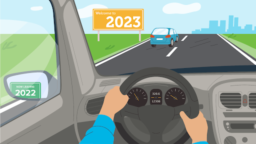 Illustration: driving in car on road with sign saying welcome to 2023.  Small sign saying 2022 can be seen in side mirror. 