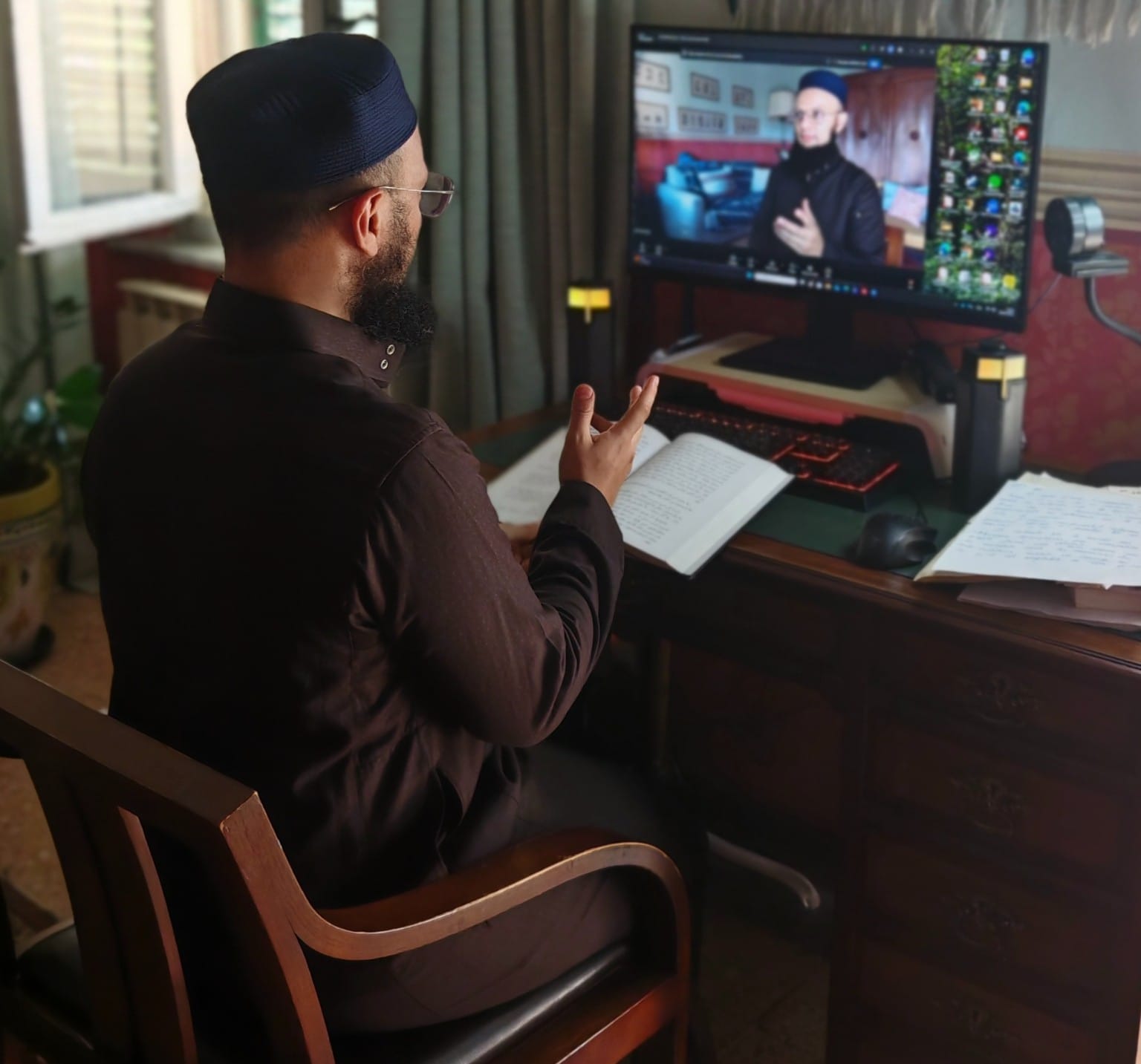 L’imam Younes enseignant en direct depuis son bureau, le livre ouvert devant lui