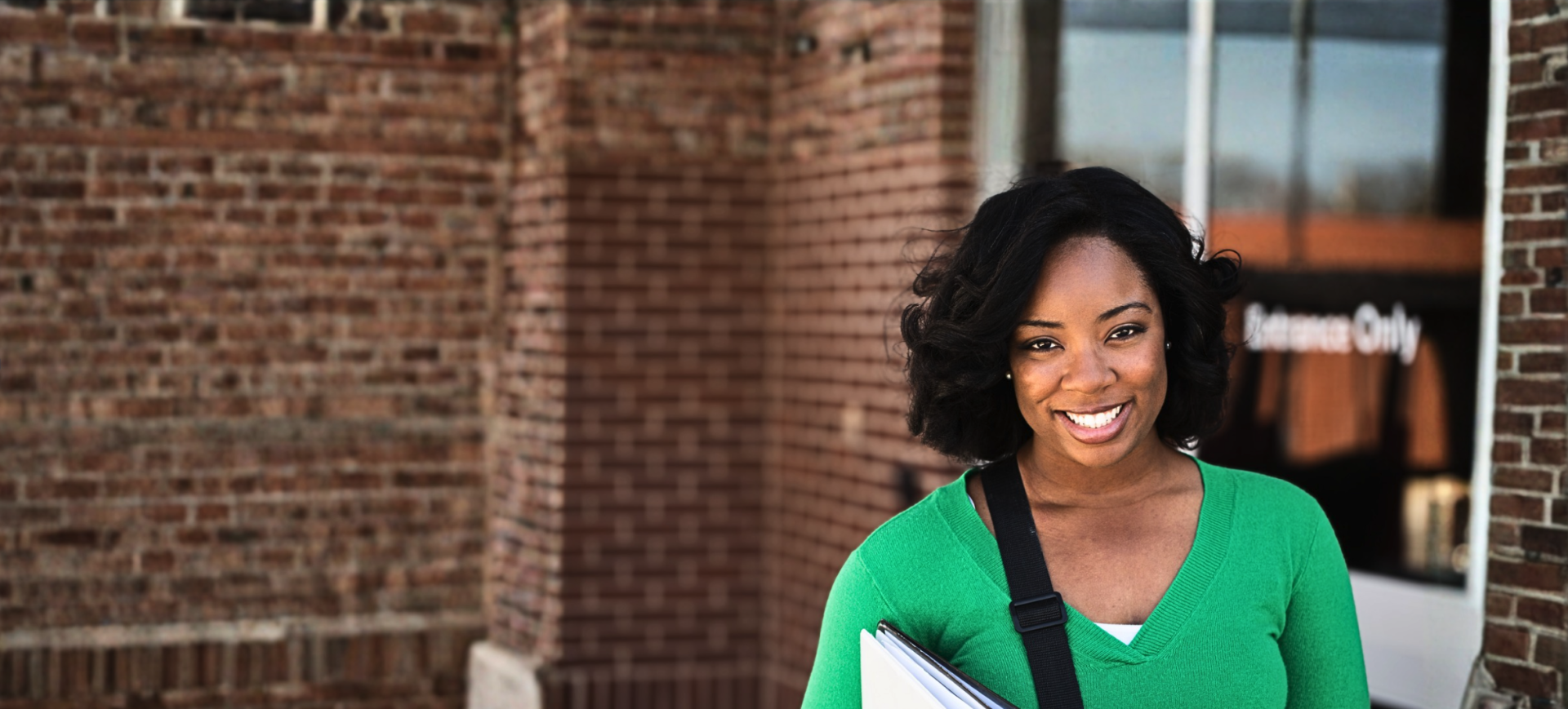 Student holding documents outside campus building