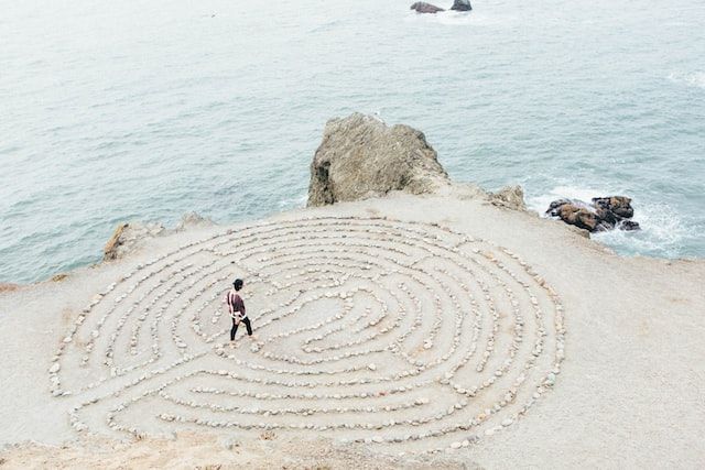 femme traversant un labyrinthe dessiné sur le sable