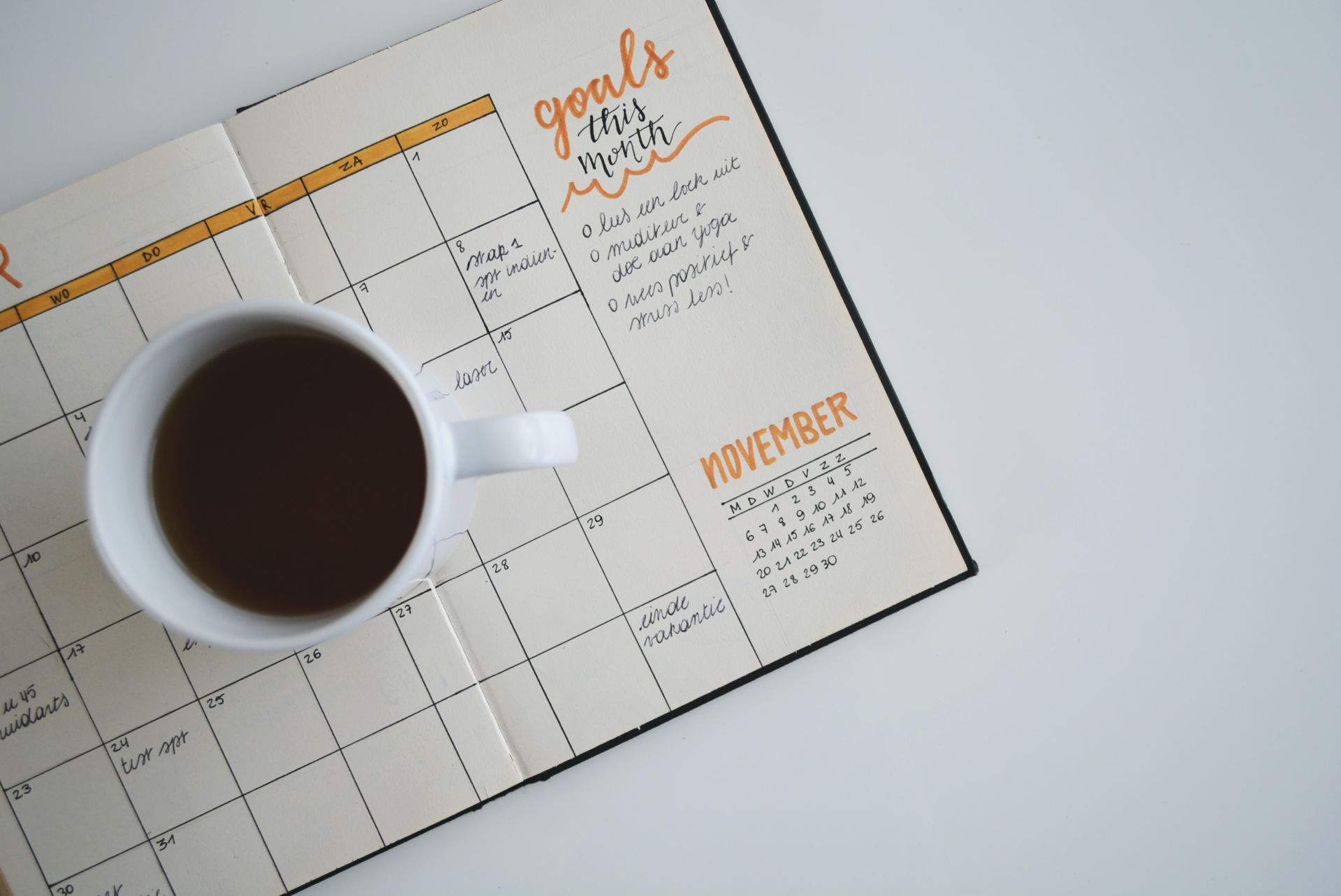 agenda avec des objectifs mensuels pour réussir sa période d'essai avec un café posé dessus