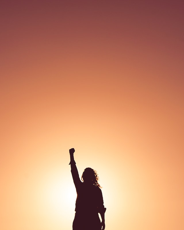 femme se tenant debout levant le poing en l’air en signe de victoire.