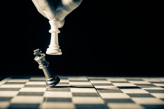 photo noir et blanc d'un jeu d'échec où un joueur fait tomber la dernière pièce