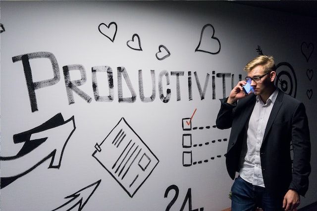 Homme au téléphone devant un mur avec l'inscription "productivity"