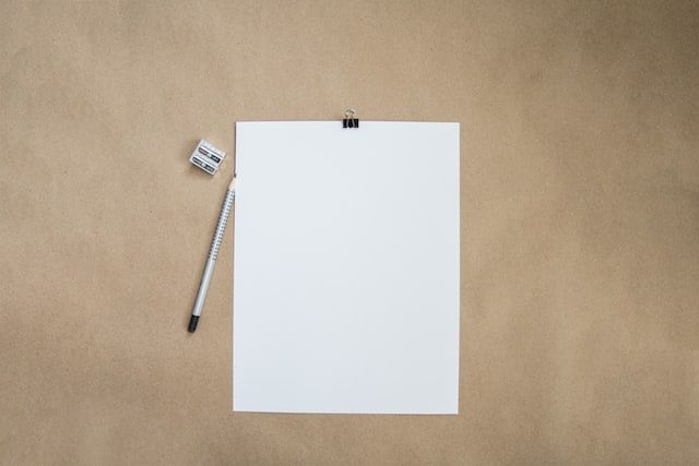 feuille blanche accompagnée d'un crayon de papier et d'un taille crayon