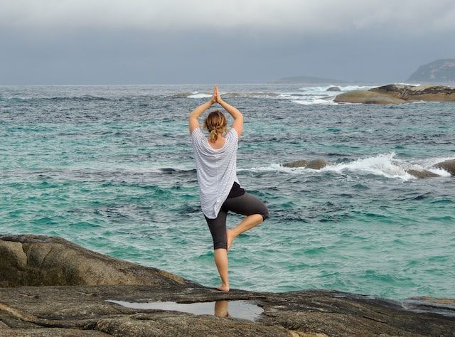 femme exécutant une posture de yoga face à la mer