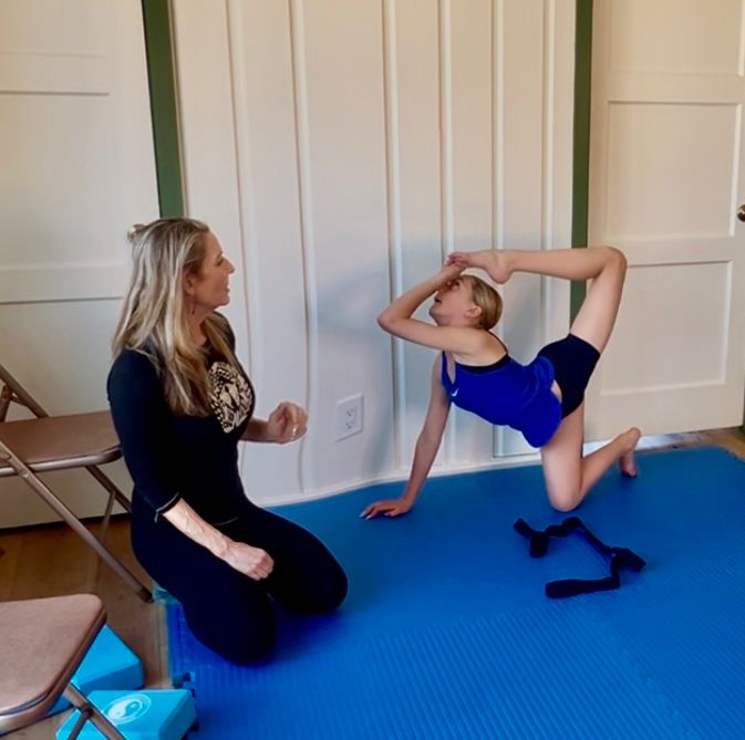 Stacey guiding young girl in stretch to increase back flexibility