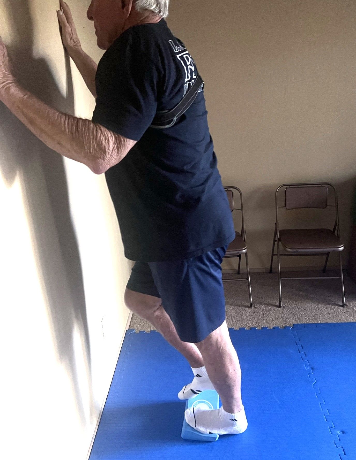 Man standing on a yoga block stretching calf & foot out