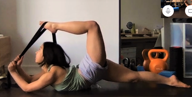 Girl on stomach stretching 1 foot back towards her head using Stacey Stretch Strap