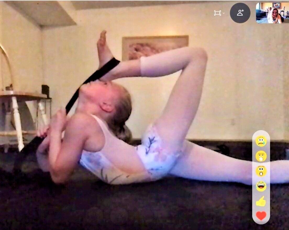 Young dancer on stomach using stretch band  to bring foot to the head in deep back arch