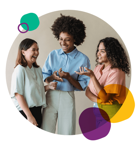 Three young women standing together laughing.