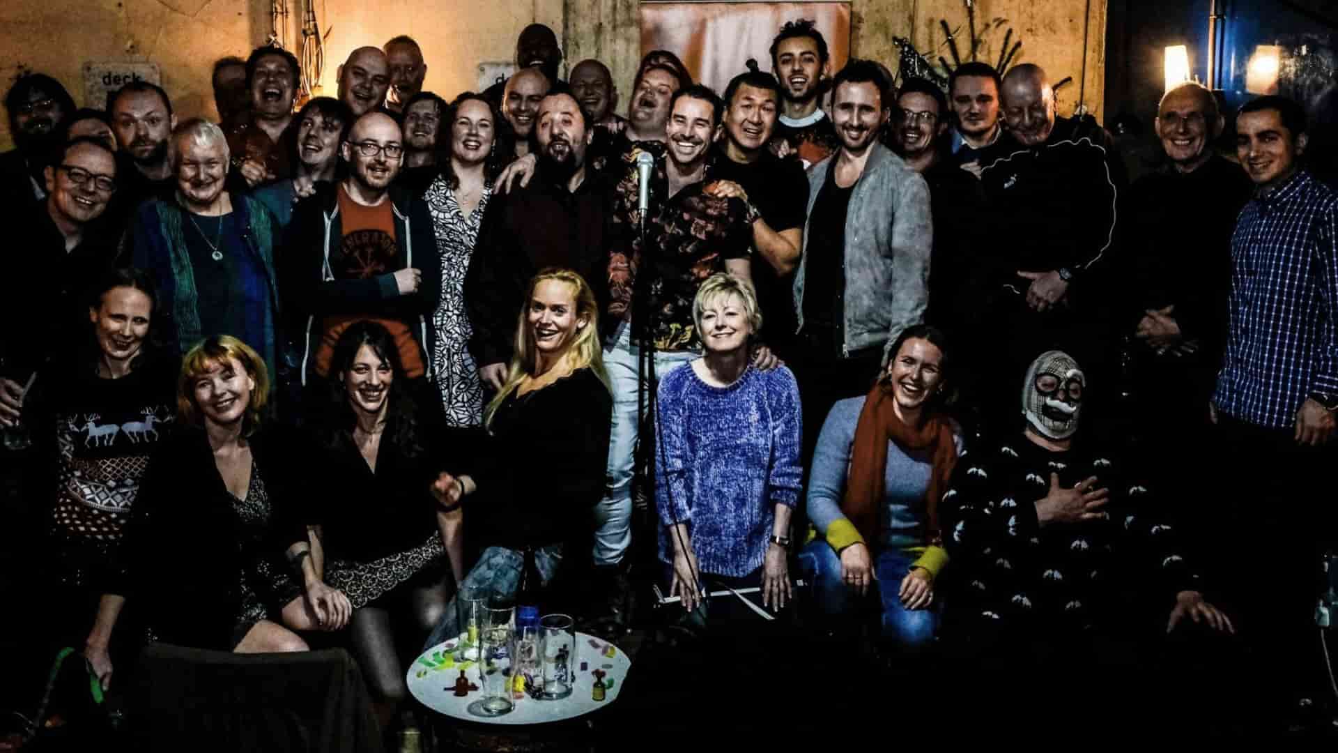Lovely team photo of a varied group gathered for a picture, young and old, laughing and smiling, at their away day event